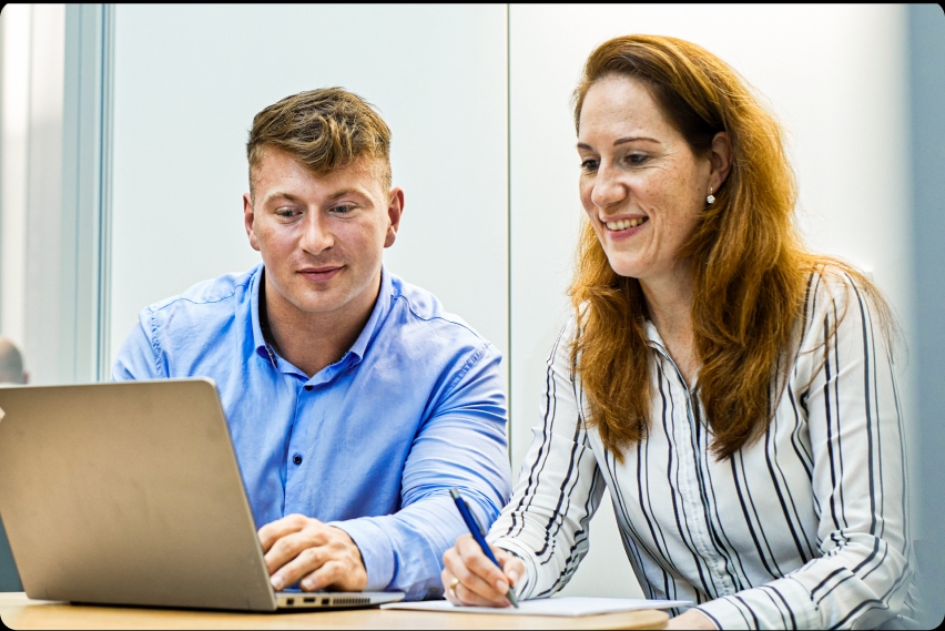 Besprechungssituation mit zwei Mitarbeitern vor einem Laptop